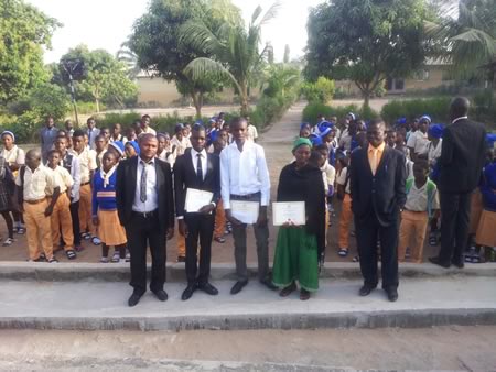 Three recipients from Good News Secondary School, with their award certificates at the Assembly ground during the 2015 Tanimu Foundation ceremony. The other pupils watched admirably.