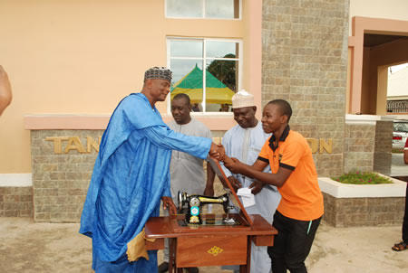 Director presenting a new sewing machine to a graduate.